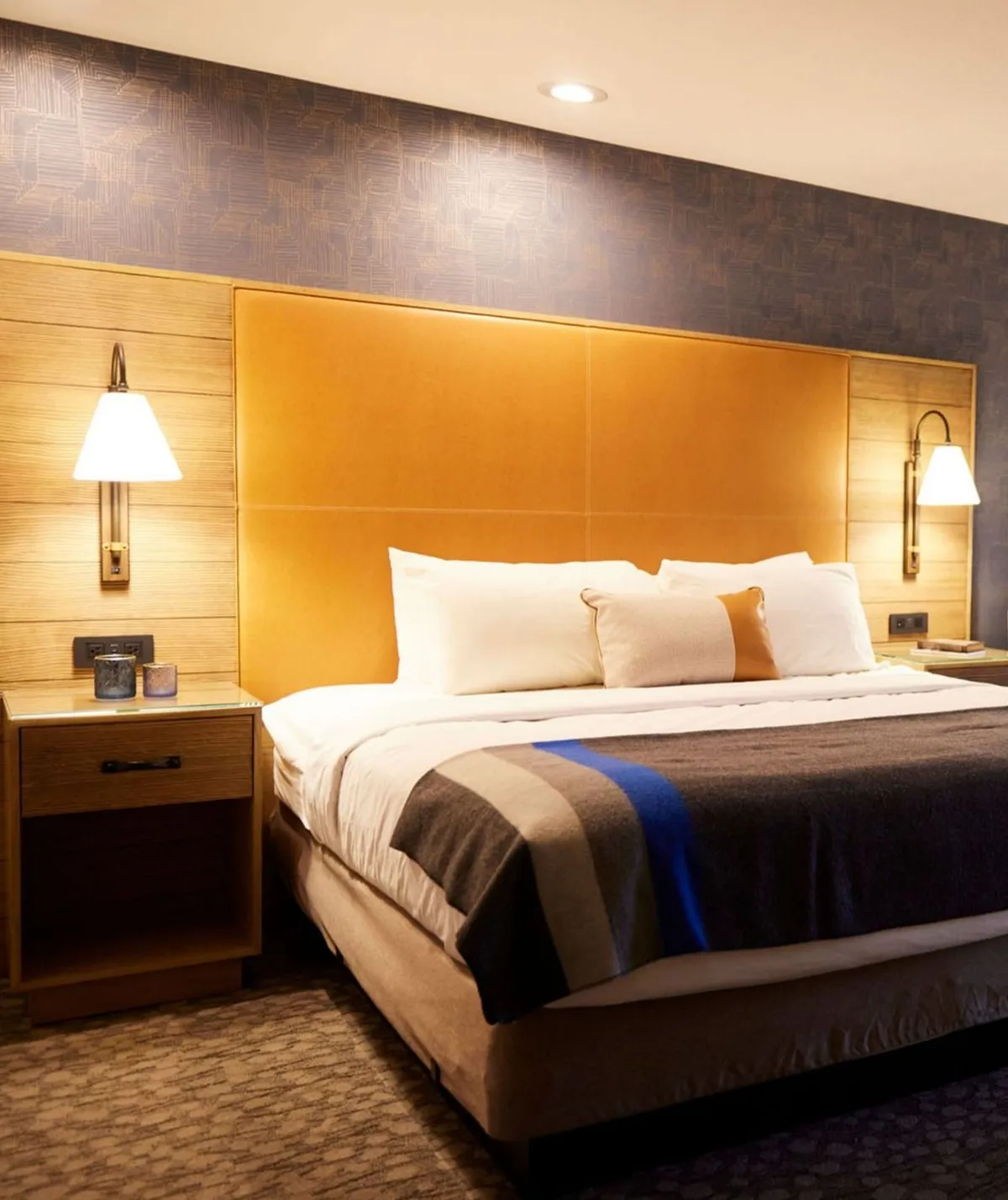 A serene and inviting studio bedroom featuring a plush bed with crisp linens, a nightstand with ambient lighting, and tranquil wall art. The soft lighting and uncluttered decor create an atmosphere perfect for rest and relaxation.